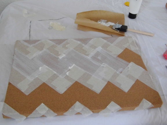 Take a plain cork board and create a stencil using masking tape. Once I had created the top chevron I measured the distance between the points in order to make the next row. Paint the areas in between the masking tape.