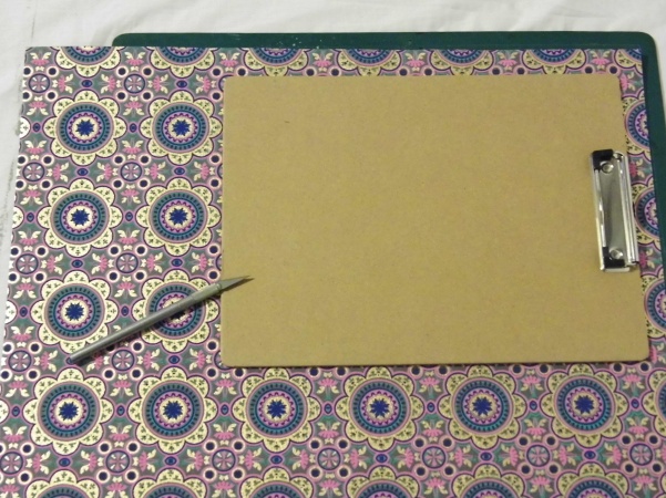 Place it on top of your decorative paper. Using your craft knife and cutting board, cut around the outline of the board.